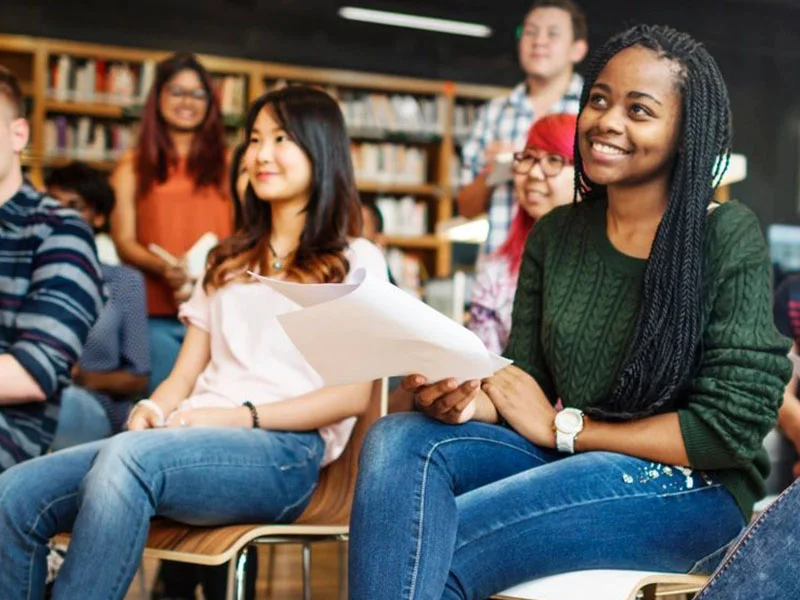 A group of people sitting in front of books.