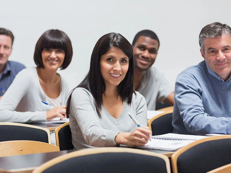 A group of people sitting at tables in front of laptops.