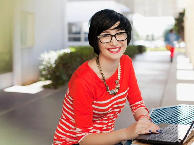 A woman sitting at a table with her laptop.